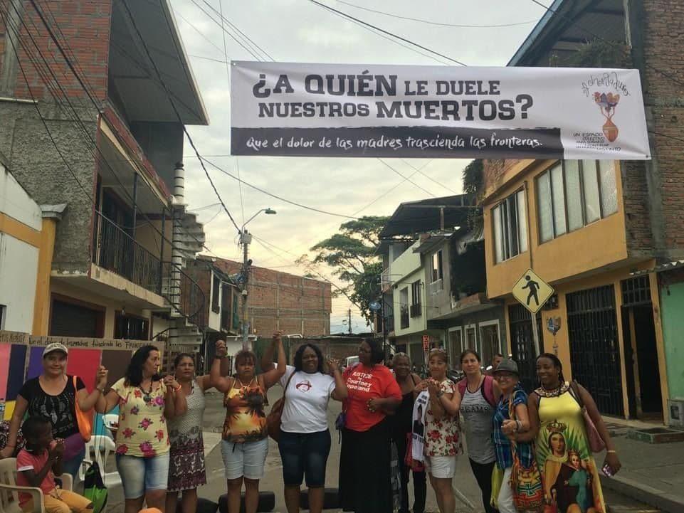 Figure 1. Maternal activists Brazilian Debora Silva and U.S.-Chicagoans Dorothy Holmes and Shapearl Welles stand centered beneath a banner in front of a Cali cultural center. The banner inscription translates: “Who feels for our dead? May the mothers’ pain transcend borders.” Photo by Global Network of Mothers in Resistance, Cali, Colombia, September 2018.